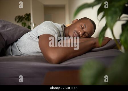 Young African man sleeping in his bed in the morning Stock Photo