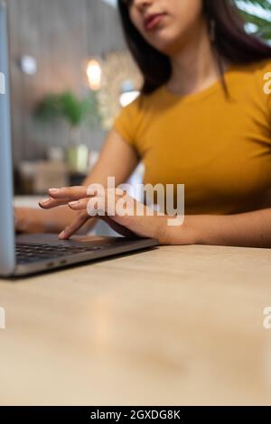 Cropped unrecognizable young female entrepreneur sitting at table and browsing netbook while working on modern workplace Stock Photo