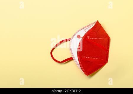 Pink KN95 or N95 FFP2 mask for protection and corona virus on pastel yellow background. Anti pollution concept. copy space, from above. Stock Photo