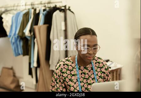 African female fashion designer working on laptop in her studio Stock Photo