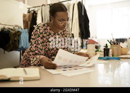 African female fashion designer looking at color samples in her studio Stock Photo