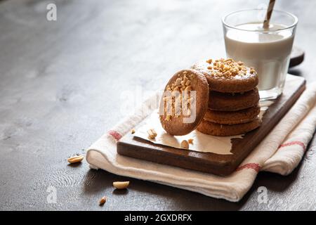 a stack of shortbread homemade cookies with peanuts on a wooden background with milk. peanut cookie. Stock Photo