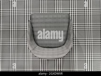 Upholstered checked pattern chair juxtaposed on matching black and white woven plaid textile in a top down view for high contrast effect for design Stock Photo