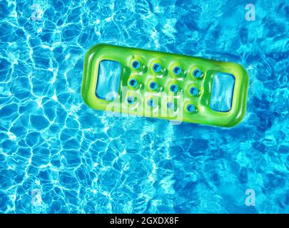 From above drone view of bright green inflatable mattress floating on blue water surface of swimming pool in sunlight in summertime Stock Photo