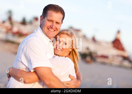Attractive Caucasian Couple Hugging at the Beach in Front of the Hotel Del Coronado, San Diego, CA. Stock Photo