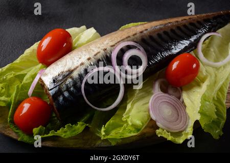 Whole cold-smoked Atlantic mackerel with cherry tomatoes, and red onion on lettuce leaves Stock Photo