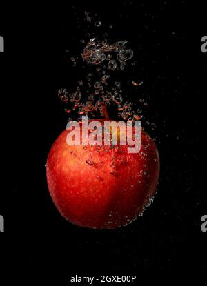 Apple splashing in water on a black background Stock Photo