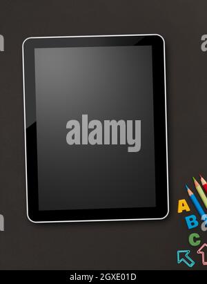 Digital tablet and school supplies on blackboard Stock Photo