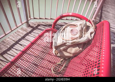 Vintage backpack is lying on red bench Stock Photo