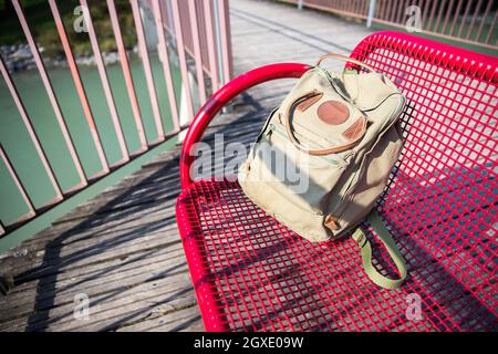Vintage backpack is lying on red bench Stock Photo
