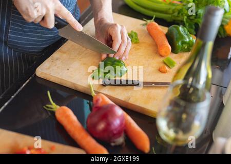 Closeup of man preparing a meal and cutting vegetables on the kitchen table Stock Photo