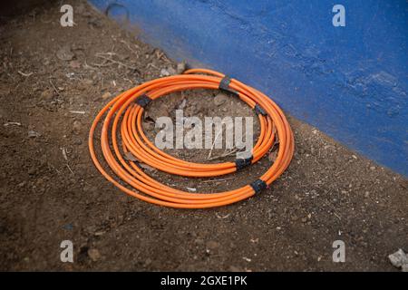 Device for modern fiber optic cables lies on the floor of a house wall Stock Photo