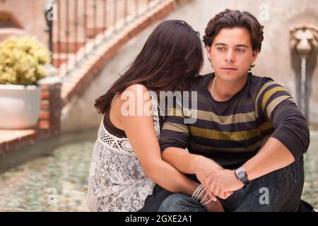 Attractive Hispanic Couple During A Serious Moment at a Fountain. Stock Photo