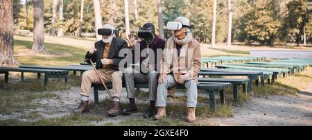 Multiethnic senior men using vr headsets in autumn park, banner Stock Photo