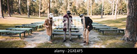 Smiling multiethnic men using vr headsets in autumn park, banner Stock Photo