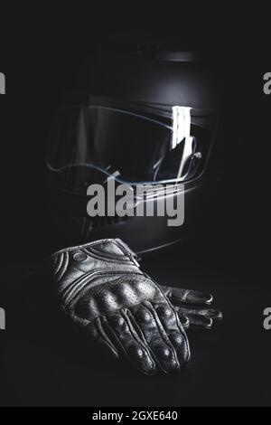 Black leather motorcycle gloves and helmet on a black background. Stock Photo