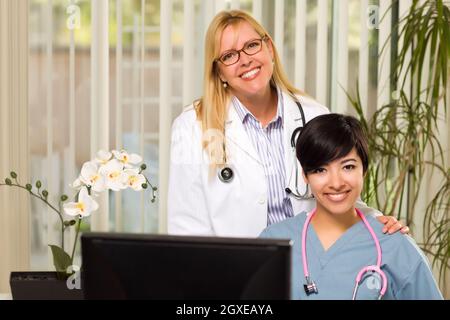 Smiling Mixed Race Female Doctors or Nurses Working Together in Office Setting. Stock Photo
