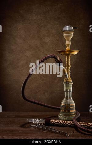 Egyptian hookah (shisha) on dark brown table on dark background. Stock Photo