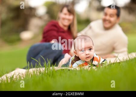 Happy Crawling Baby Boy and Mixed Race Parents Playing in the Park.