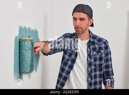 Casual house painter painting a wall with paint roller Stock Photo