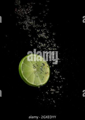 Lime splashing in water on a black background Stock Photo