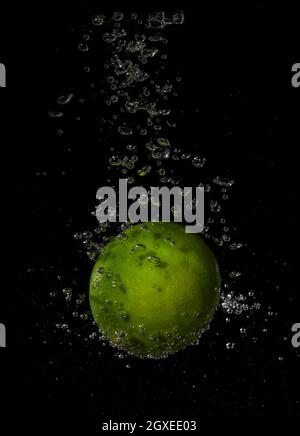 Lime splashing in water on a black background Stock Photo