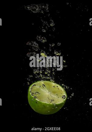 Lime splashing in water on a black background Stock Photo