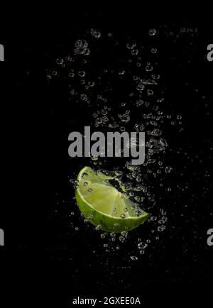 Lime splashing in water on a black background Stock Photo