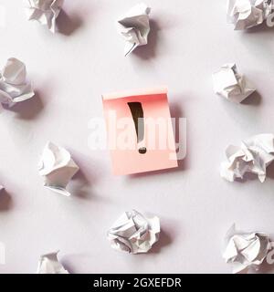 Exclamation mark and crumpled paper balls on purple background. Solution concept Stock Photo