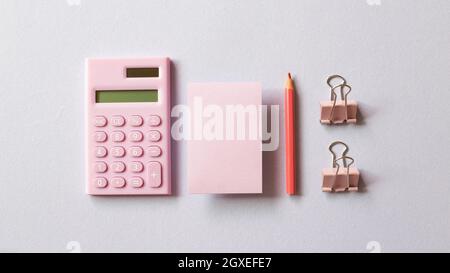 Pink digital calculator, memo pad, pencil, clip on purple background. top view, copy space Stock Photo