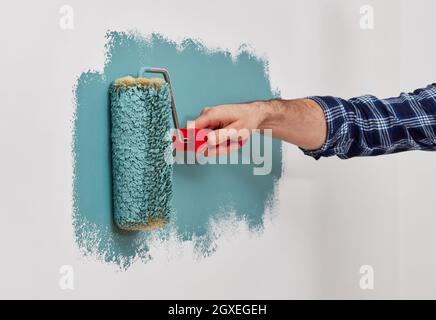 Male hand painting wall with paint roller Stock Photo