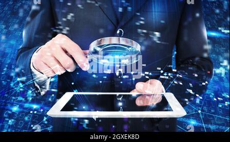 Businessman analyzes a computer system for virus and hacker attacks with lens Stock Photo