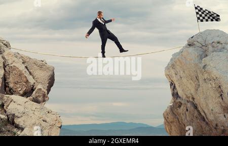 Business concept of businessman who overcome the problems reaching the finish line on a rope Stock Photo