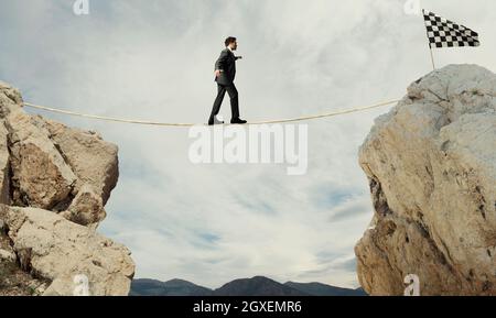 Business concept of businessman who overcome the problems reaching the finish line on a rope Stock Photo