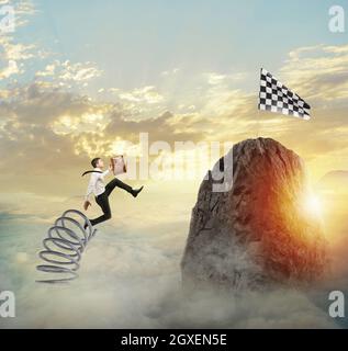 Businessman jumping on a spring to reach the flag at the top of the mountain. Achievement business goal and Difficult career concept Stock Photo