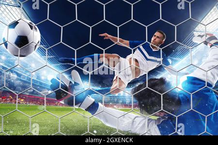 Soccer striker hits the ball with an acrobatic jumping kick Stock Photo