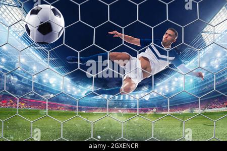 Soccer striker hits the ball with an acrobatic jumping kick Stock Photo