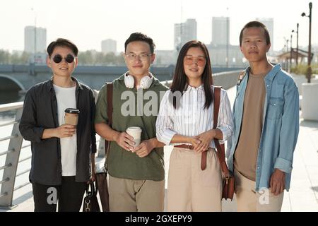 Group of happy young colleagues standing against riverside on sunny day Stock Photo