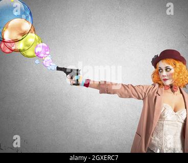 Clown thief shoots bubbles from her gun Stock Photo