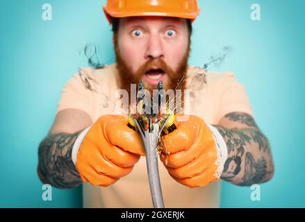Incompetent worker electrician is unsure about his work Stock Photo