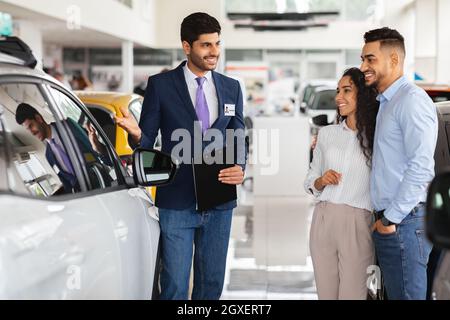 Smiling middle-eastern couple looking at white car Stock Photo