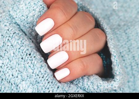Female hand in a gray knitted sweater with a beautiful glossy manicure -  burgundy, dark red, cherry color nails on background of silver Christmas  tins Stock Photo - Alamy