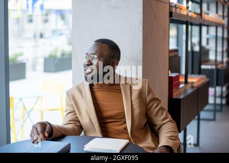 Happy young businessman looking through window of contemporary bookshop Stock Photo