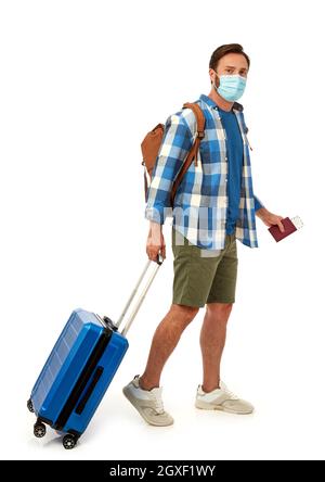 Tourist with backpack and suitcase wearing a face mask on white background Stock Photo