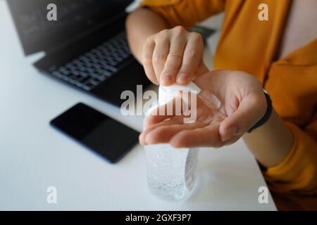 Hand sanitizer. Close up of business woman hands sanitizing with alcohol gel in the office. Stock Photo