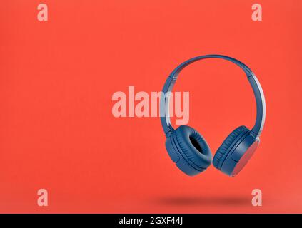 Wireless blue headphones on red background Stock Photo