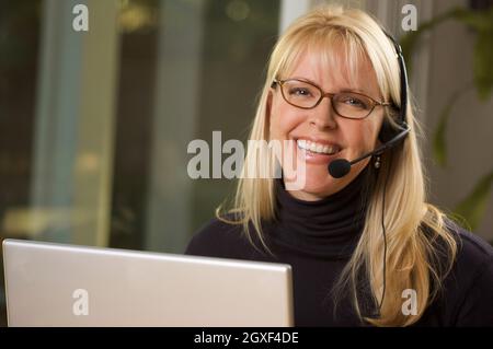 Attractive businesswoman smiles as she talks on her phone headset. Stock Photo
