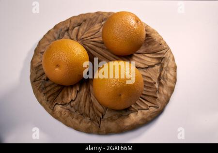 Three oranges on a wooden tray on a white isolated background Stock Photo