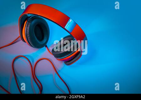 Closeup Photo of a Big Red Headphones on the Table. Stylish Accessory for Dj. Musical Fan. Equipment for a Home Schooling. Photo with Copy Space. Stock Photo