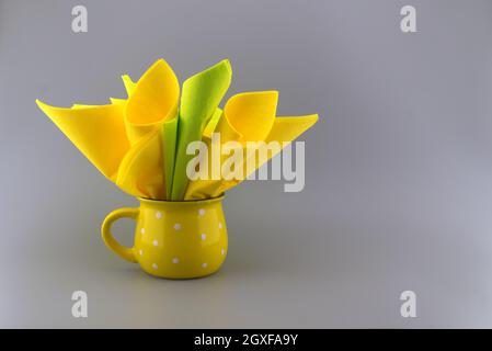 Yellow napkins placed in the yellow cup on gray background with free copy space Stock Photo